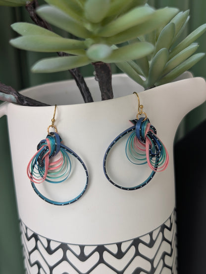 Colorful hoop earrings on a white stand with a plant in the background