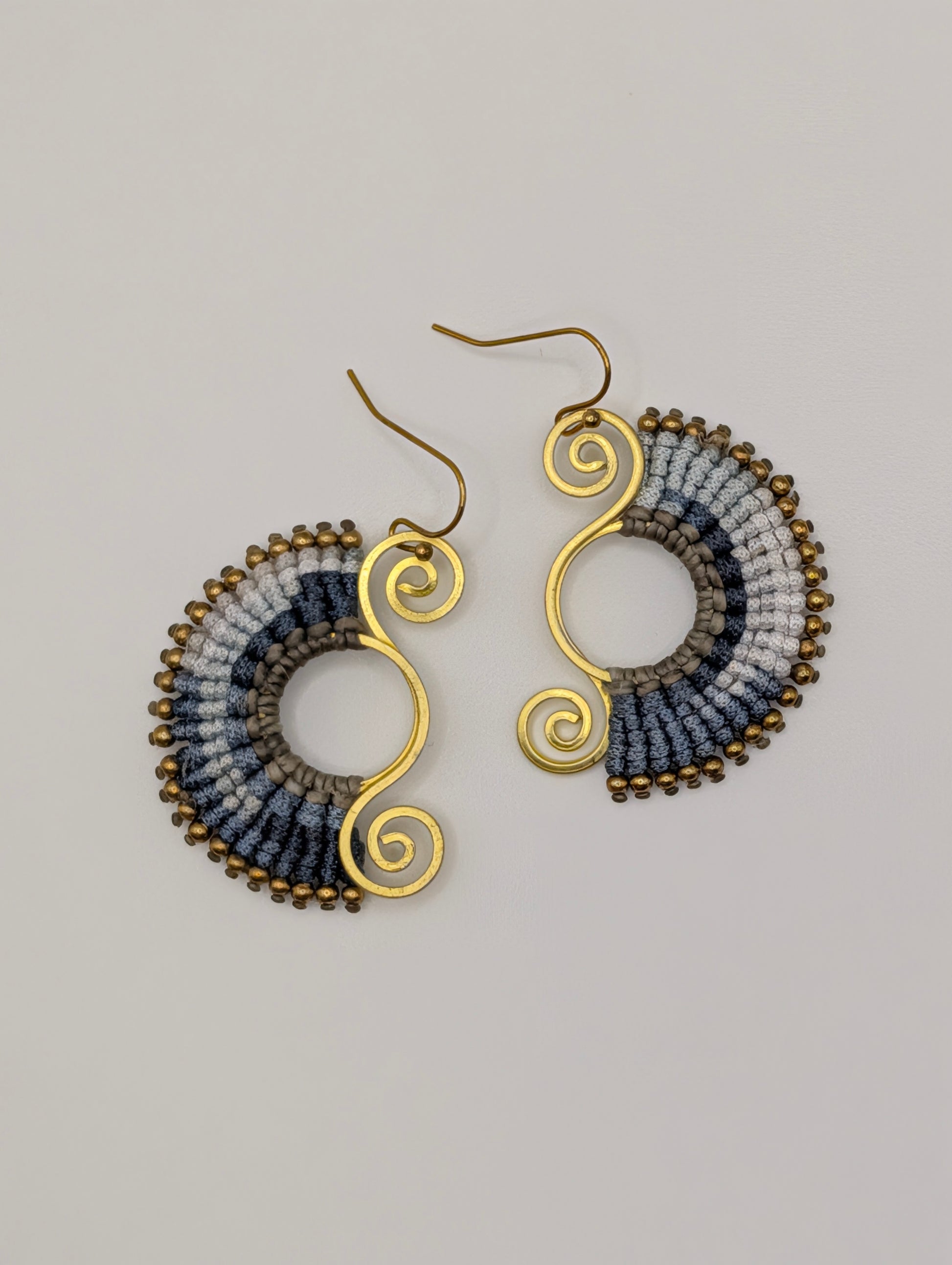 Pair of earrings with gold and multicolored design on a gray background